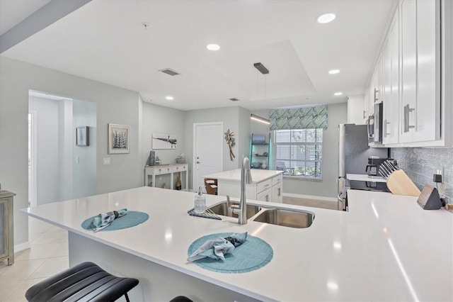 kitchen featuring kitchen peninsula, a kitchen bar, sink, light tile patterned floors, and white cabinetry