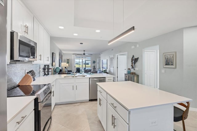 kitchen featuring kitchen peninsula, stainless steel appliances, sink, light tile patterned floors, and white cabinetry