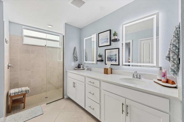 bathroom with tiled shower, vanity, and tile patterned floors