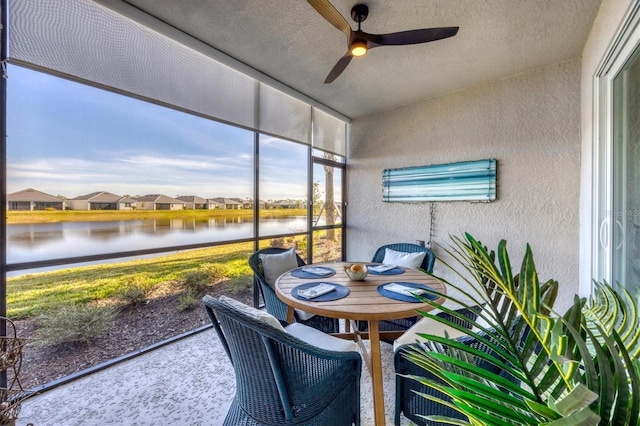 sunroom featuring ceiling fan and a water view