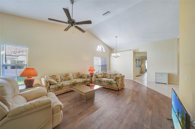 living room featuring ceiling fan with notable chandelier, light wood-type flooring, and lofted ceiling