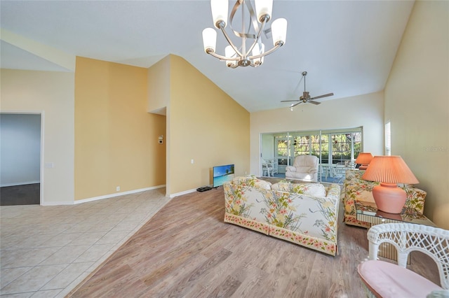 tiled living room featuring lofted ceiling and ceiling fan with notable chandelier