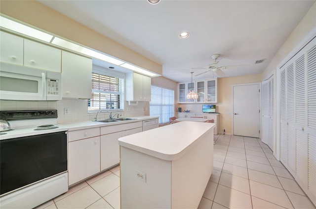 kitchen featuring white appliances, ceiling fan, sink, a center island, and white cabinetry