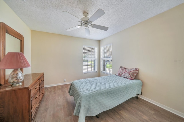 bedroom with ceiling fan, wood-type flooring, and a textured ceiling