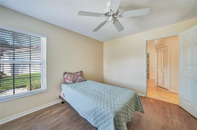 bedroom with hardwood / wood-style flooring, ceiling fan, a textured ceiling, and multiple windows