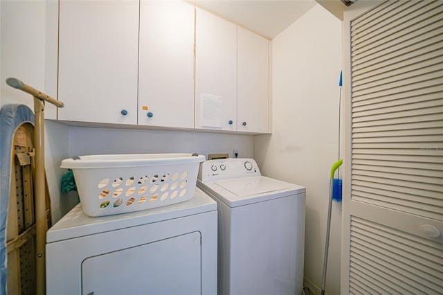 clothes washing area with cabinets and separate washer and dryer