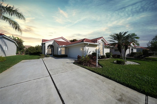 mediterranean / spanish-style house with a garage and a lawn