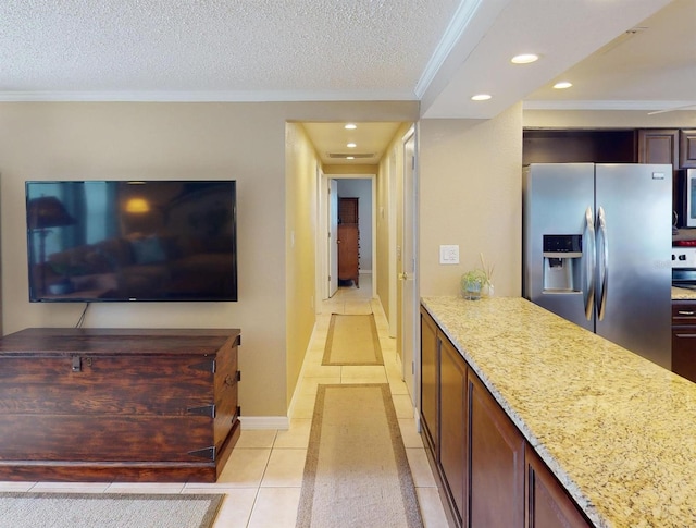 kitchen with light stone counters, ornamental molding, a textured ceiling, light tile patterned floors, and stainless steel fridge with ice dispenser