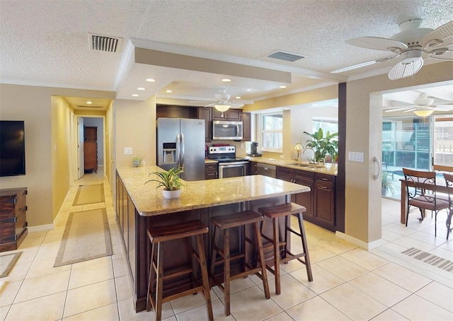 kitchen with a breakfast bar, sink, light tile patterned flooring, and appliances with stainless steel finishes