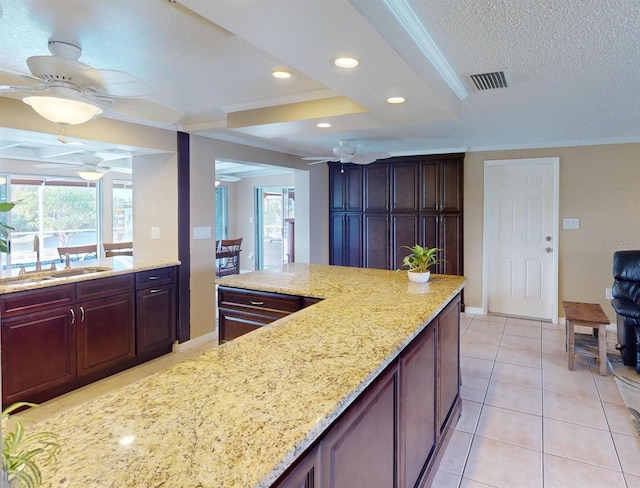 kitchen with light stone counters, ornamental molding, a textured ceiling, sink, and light tile patterned floors