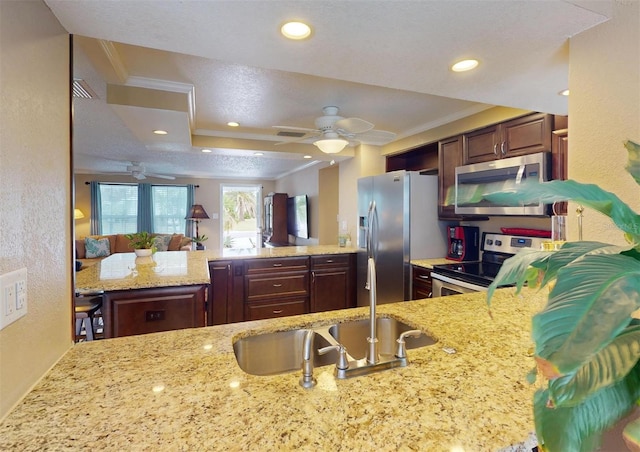 kitchen with light stone counters, kitchen peninsula, crown molding, and appliances with stainless steel finishes