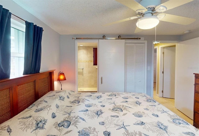 bedroom with ceiling fan, a barn door, ensuite bathroom, a textured ceiling, and a closet