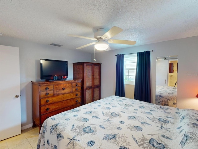 tiled bedroom with ceiling fan and a textured ceiling