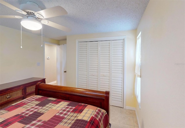 bedroom with light tile patterned floors, a textured ceiling, a closet, and ceiling fan