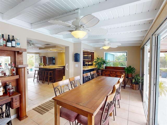 dining space featuring beamed ceiling, ceiling fan, light tile patterned floors, and a wealth of natural light