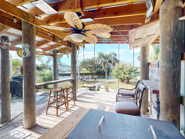 exterior space with ceiling fan, a water view, and an outdoor bar