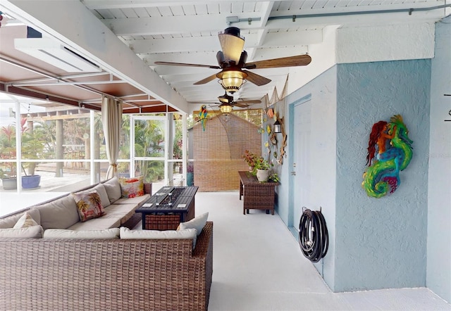 sunroom featuring beam ceiling and ceiling fan