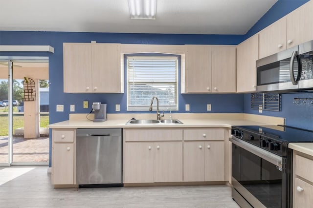 kitchen featuring sink, light brown cabinets, stainless steel appliances, light hardwood / wood-style flooring, and lofted ceiling