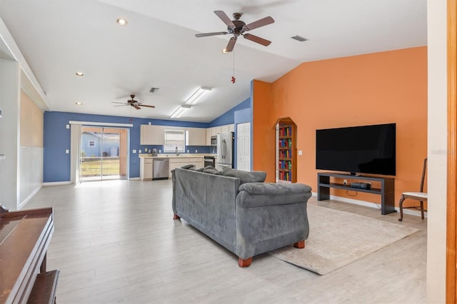 living room with ceiling fan, light hardwood / wood-style floors, and vaulted ceiling