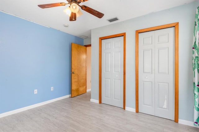 unfurnished bedroom featuring two closets, light hardwood / wood-style flooring, and ceiling fan