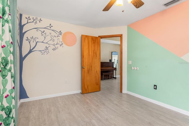 empty room with ceiling fan and light hardwood / wood-style flooring