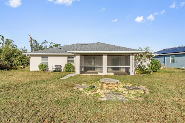 back of property with a sunroom, a yard, and an outdoor fire pit