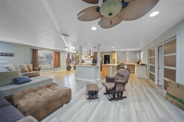 living room featuring ceiling fan, a textured ceiling, and light wood-type flooring