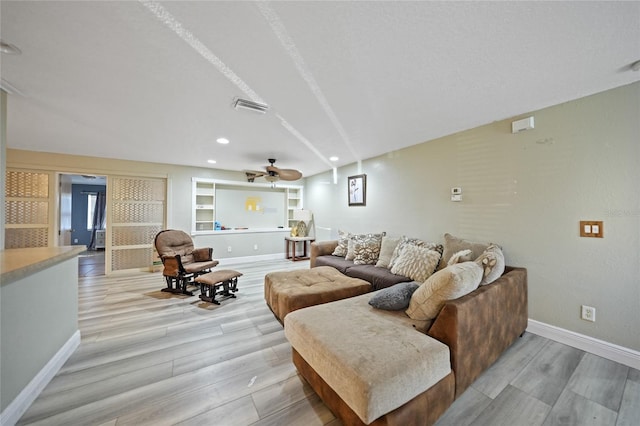 living room featuring ceiling fan, built in features, and light hardwood / wood-style flooring