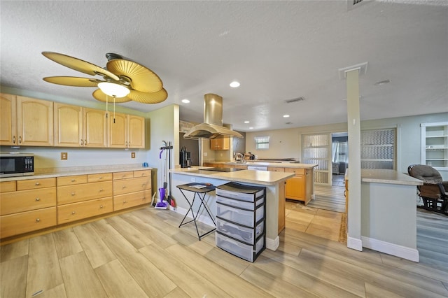 kitchen with a center island, light brown cabinets, a kitchen bar, island range hood, and light wood-type flooring