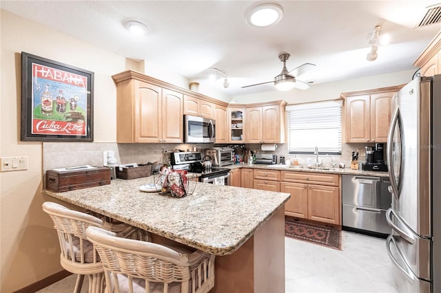 kitchen with light brown cabinets, sink, a breakfast bar area, kitchen peninsula, and stainless steel appliances