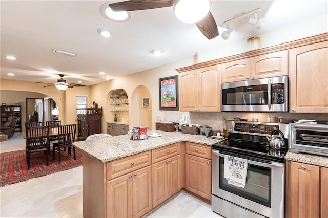 kitchen featuring light stone countertops, ceiling fan, tasteful backsplash, kitchen peninsula, and appliances with stainless steel finishes