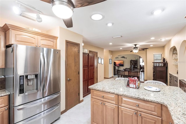 kitchen featuring ceiling fan, light stone counters, stainless steel fridge with ice dispenser, and light brown cabinetry