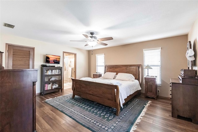 bedroom featuring ensuite bath, ceiling fan, dark hardwood / wood-style flooring, and multiple windows