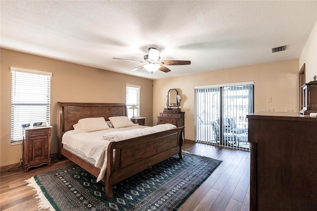 bedroom featuring access to outside, ceiling fan, a textured ceiling, and hardwood / wood-style flooring