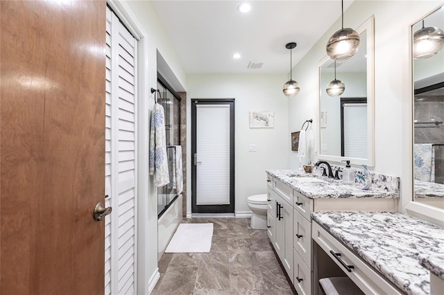 full bathroom featuring shower / bath combination with glass door, vanity, and toilet