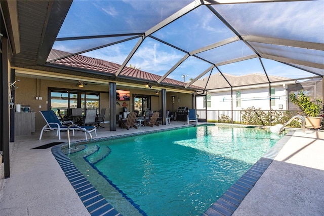 view of pool featuring glass enclosure, ceiling fan, and a patio area