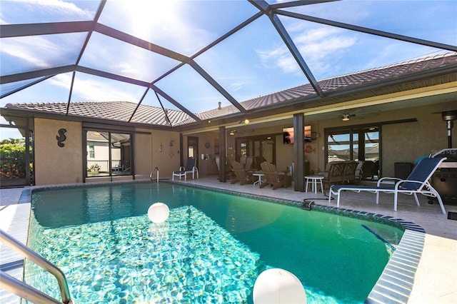 view of swimming pool with ceiling fan, a patio, and glass enclosure