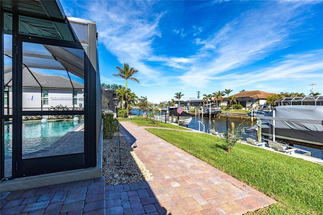 dock area with a lanai, a yard, and a water view