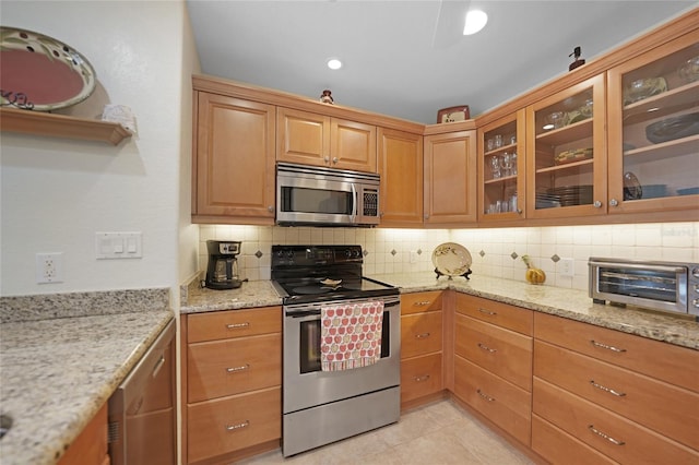 kitchen with decorative backsplash, light stone countertops, stainless steel appliances, and light tile patterned flooring