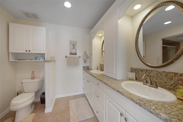 bathroom with toilet, vanity, and tile patterned flooring