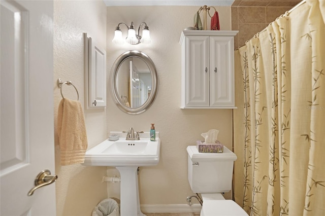 bathroom featuring toilet and curtained shower