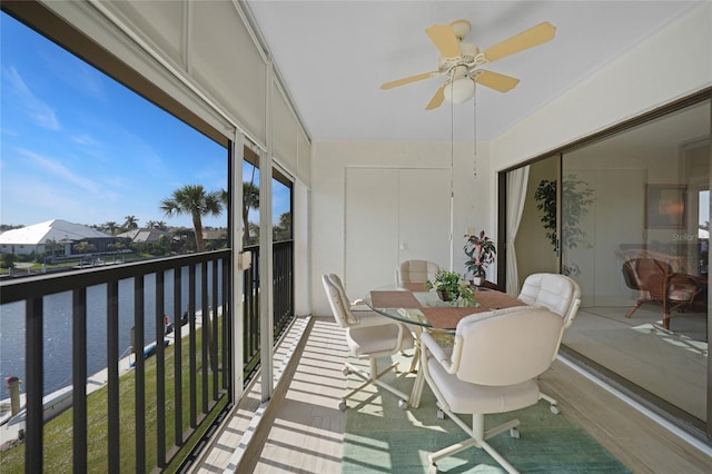 sunroom / solarium with ceiling fan and a water view