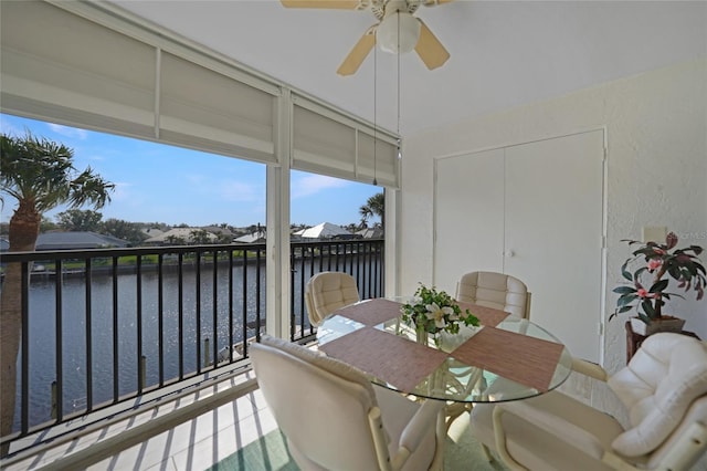 sunroom / solarium featuring ceiling fan and a water view