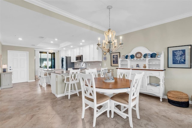 dining room with an inviting chandelier, a raised ceiling, ornamental molding, and sink