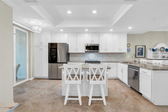 kitchen featuring light stone countertops, kitchen peninsula, appliances with stainless steel finishes, and a tray ceiling