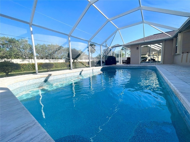 outdoor pool featuring glass enclosure and a patio