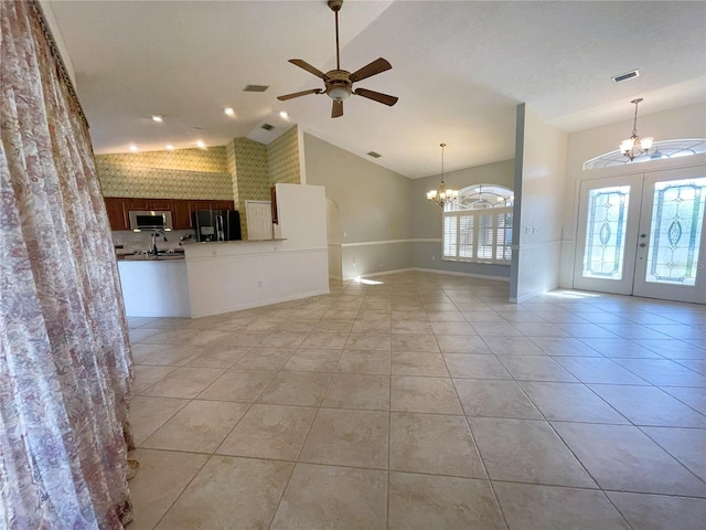 unfurnished living room with ceiling fan with notable chandelier, vaulted ceiling, light tile patterned floors, and french doors