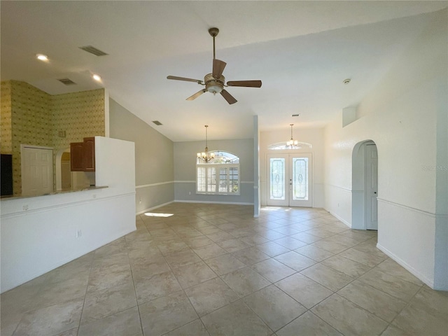 unfurnished living room with french doors, ceiling fan with notable chandelier, vaulted ceiling, and light tile patterned floors