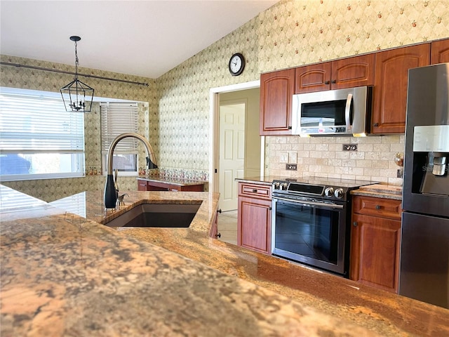 kitchen with sink, decorative light fixtures, vaulted ceiling, a notable chandelier, and stainless steel appliances