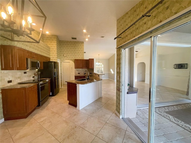 kitchen with pendant lighting, an inviting chandelier, black appliances, a center island with sink, and sink